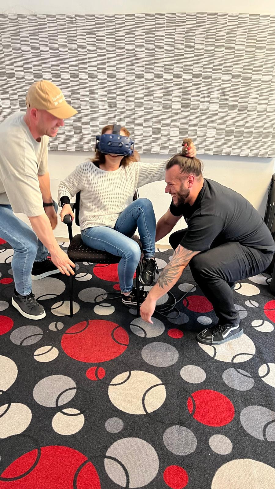 Účastníčka teambuildingu s VR okuliarmi a kolegami