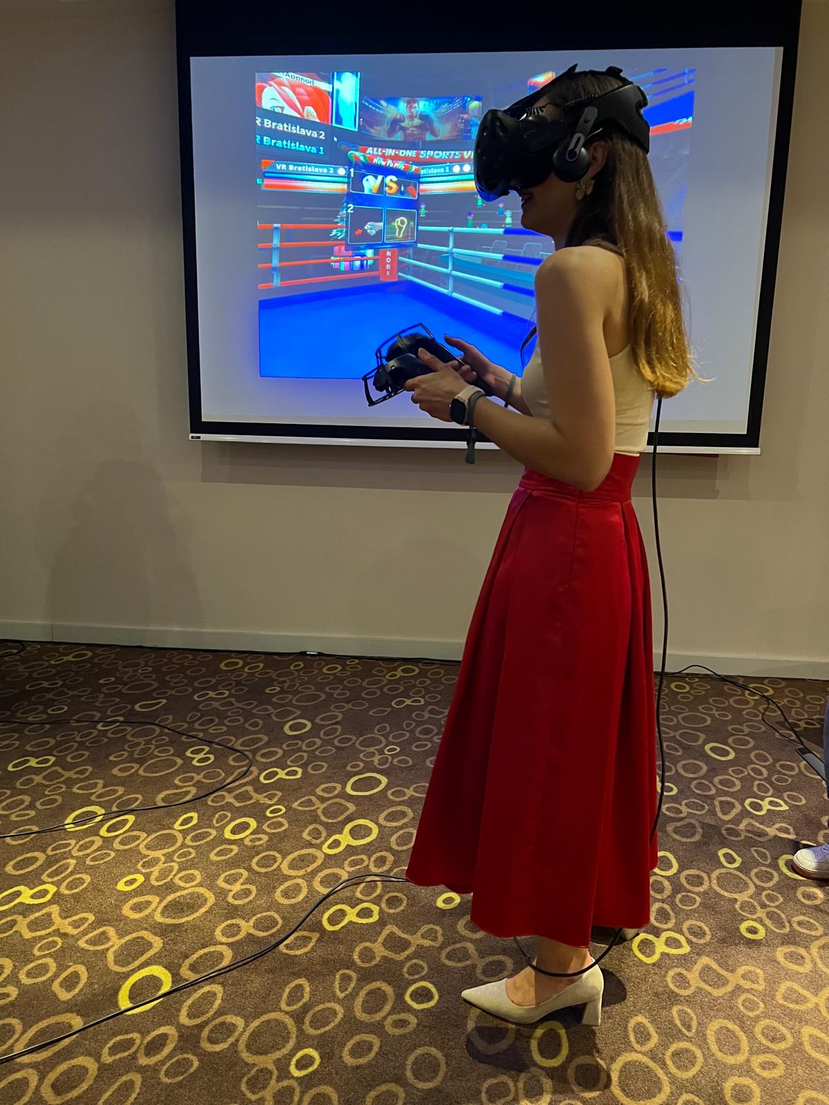 Účastníčka eventu s VR okuliarmi a ovládačmi